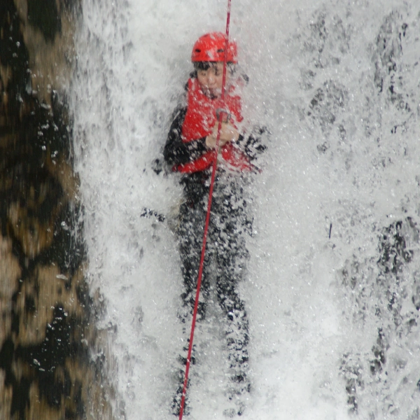 みなかみウォーターフォックスキャニオニングで滝下り（ラッペリング）に挑戦する様子。Thrill-seeker descending a steep canyon waterfall on a Minakami water fox canyoning adventure in Japan.