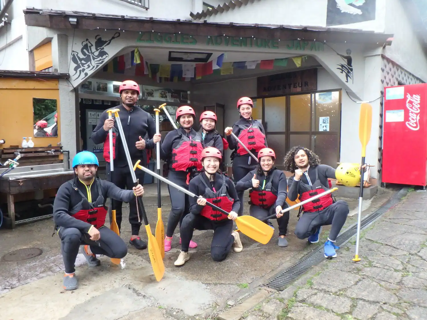 (水上)みなかみラフティング参加者がアドベンチャーベースキャンプでみなかみ半日ラフティング体験前にパドルを持ってポーズ、Minakami rafting participants posing with paddles at adventure base camp before minakami half day rafting experience.