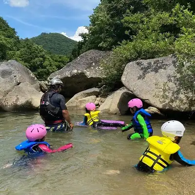 ミナカミ川を滑る赤いヘルメットと救命胴衣を着た子供, kid wearing red helmat and life jacket sliding in minakami river 